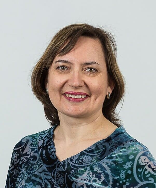 Professional portrait of a woman with shoulder-length brown hair and a patterned blue top.