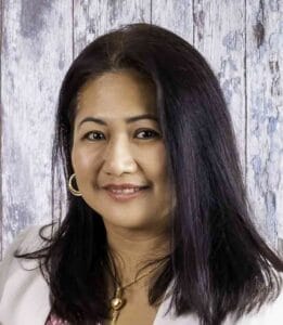 Professional portrait of a woman with dark hair and gold jewelry, representing Equana Minds.