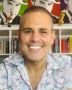 Smiling man in front of colourful pop art and bookshelf at Equana Minds.