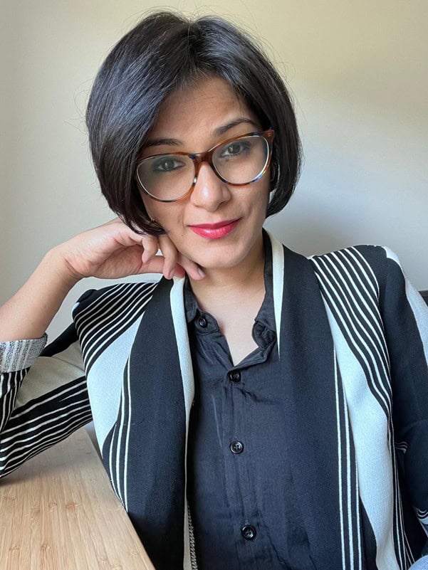Professional woman with glasses and short black hair smiling at Equana Minds.