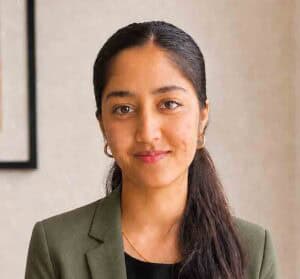 Professional portrait of Mona Murthyamma, woman with dark hair and earrings.