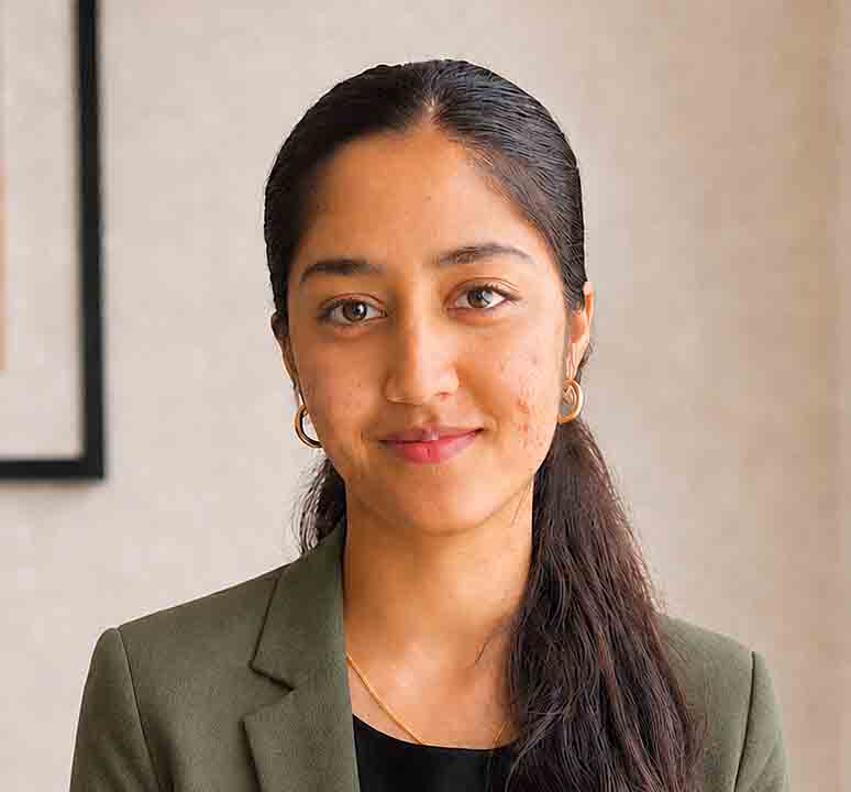 Professional portrait of Mona Murthyamma, woman with dark hair and earrings.